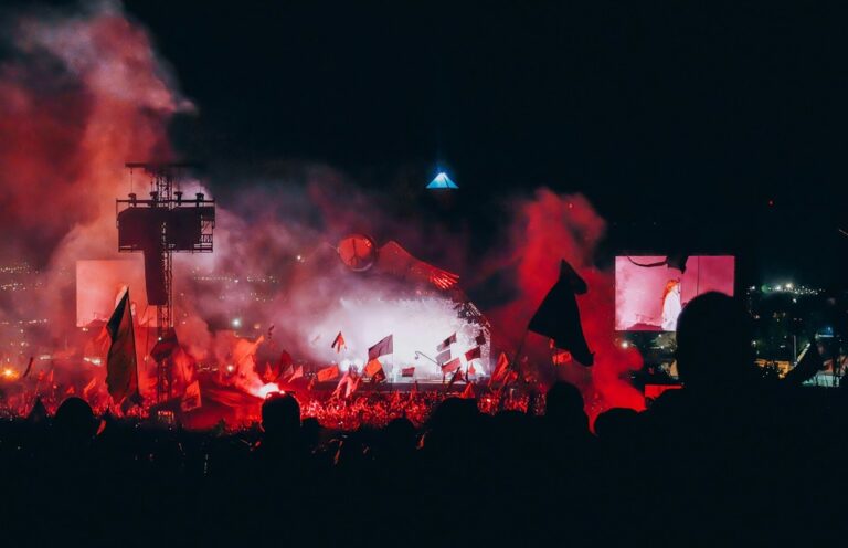 The Pyramid Stage at Glastonbury Festival lit up in red at night. By Annie Spratt on Unsplash