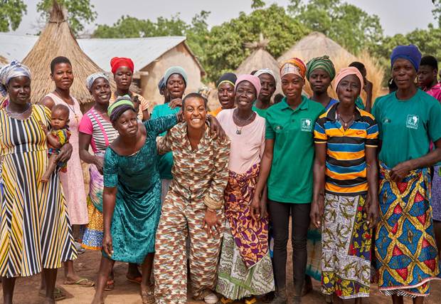 A group of people in an Africa village smiling at the camera. They have been supported by Tree Aid