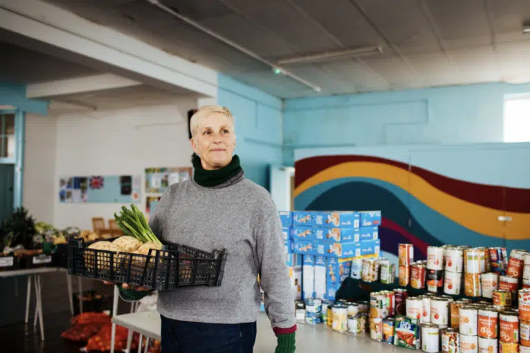 A woman holding a tray of vegetables in a foodbank. Neighbourly charity - BS3 Community Development