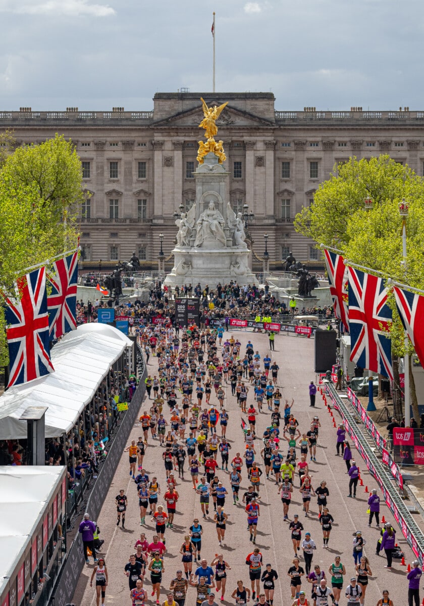 Runners in the TCS London Marathon running down the Mall with Buckingham Palace behind them to the finish line.