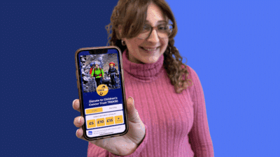 Give A Little Champion app on a phone held by a woman with glasses