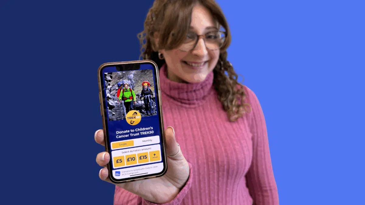Give A Little Champion app on a phone held by a woman with glasses