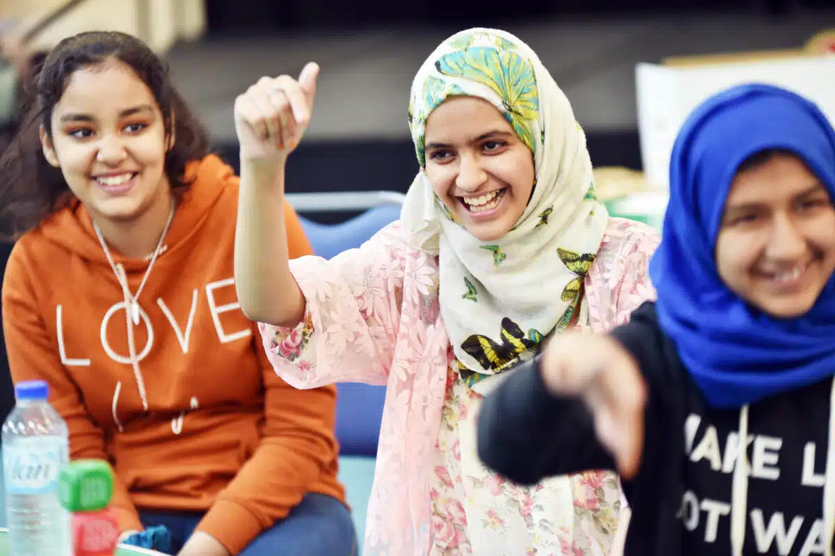 Three girls smiling, and one with a thumbs up sign, at a GIrls Activities day in Leeds.