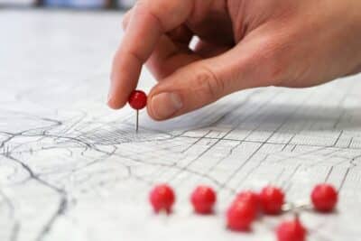 Red map pins being placed on a map.