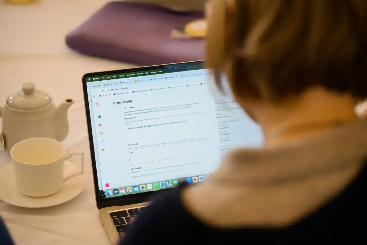 Looking over a woman's shoulder at Raiser in use on screen at its launch event.