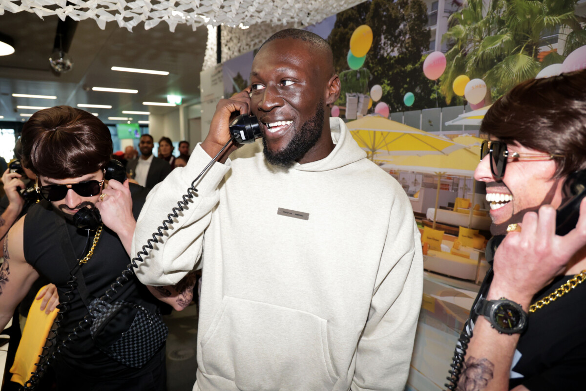 Stormzy smiles as he talks on a phone at ICAP Charity Day in London.