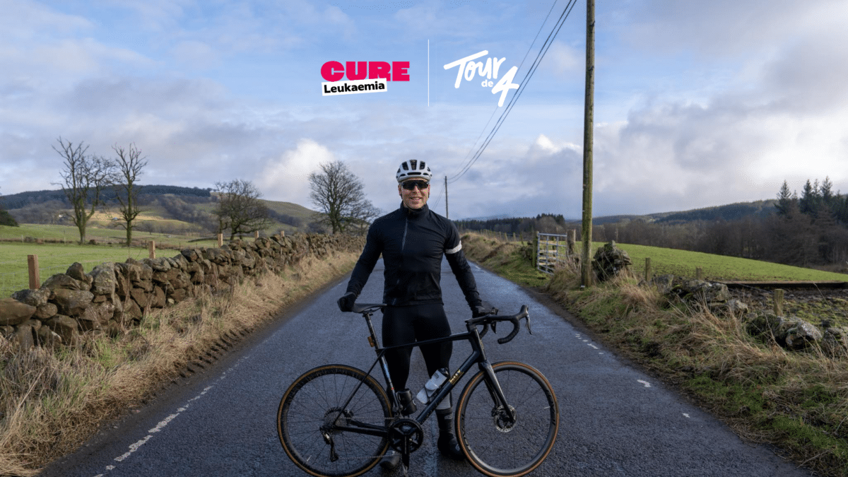 Sir Chris Hoy with a bike on a long road, with the Tour d4 logo above him
