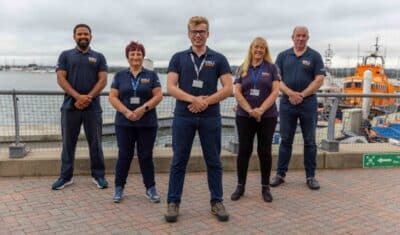 Five members of the RNLI face-to-face fundraising team, standing in front of a RNLI lifeboat.