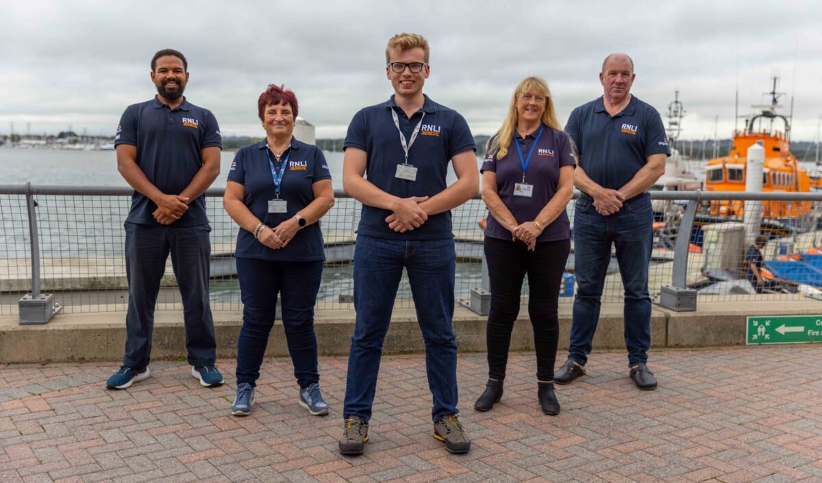 Five members of the RNLI face-to-face fundraising team, standing in front of a RNLI lifeboat.