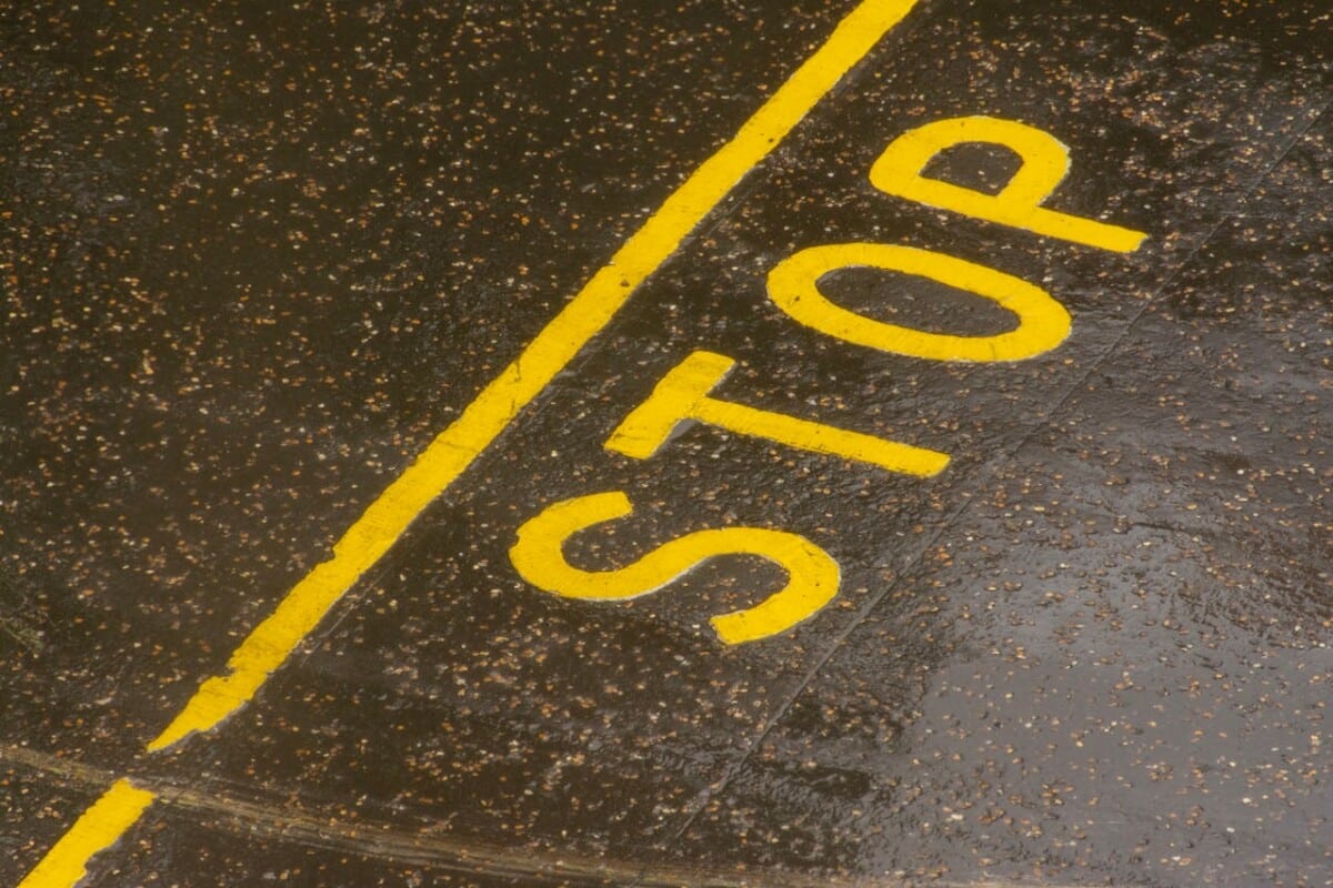 Yellow stop sign painted on a wet road surface.