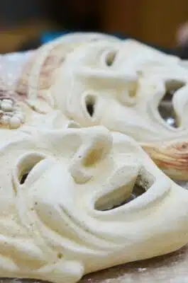 Two white plaster face masks symbolising tragedy and comedy.